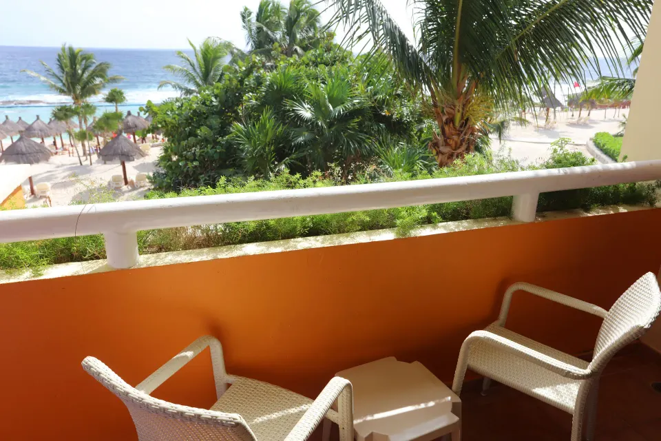Balcony chairs overlooking palm trees beach and ocean at Bahia Principe Luxury Akumal