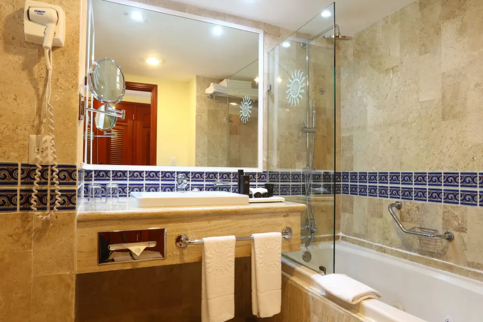 Bathroom in a Junior Suite with tub, glass shower screen and vanity at Bahia Principe Luxury Akumal