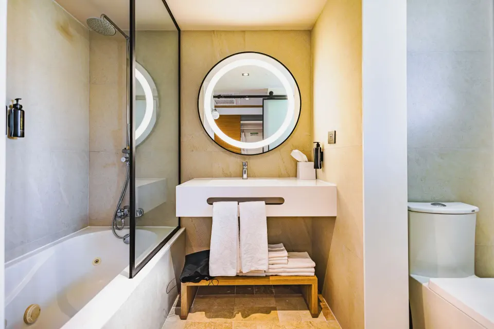 Junior Suite Swim Up bathroom with bathtub, vanity and round mirror at Bahia Principe Luxury Akumal