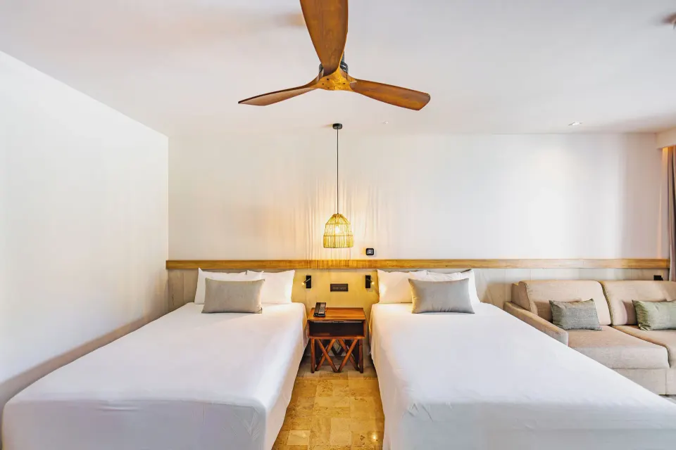Twins beds and seating area in a Junior Suite Swim Up at Bahia Principe Luxury Akumal