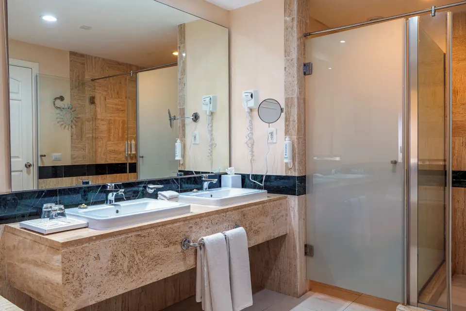 Bathroom with double sinks and glass-enclosed shower in junior suite at Bahia Principe Luxury Akumal