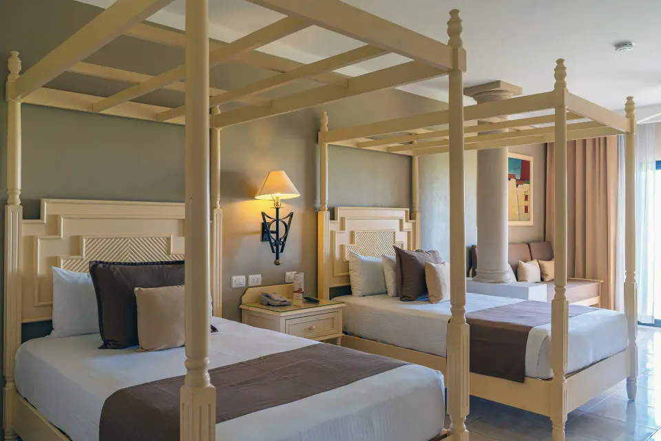 Close-up of two canopy beds and bedside lamp in a junior suite at Bahia Principe Luxury Akumal