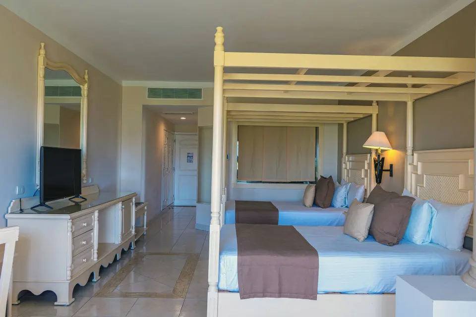 View from room entrance of junior suite with two canopy beds and television at Bahia Principe Luxury Akumal