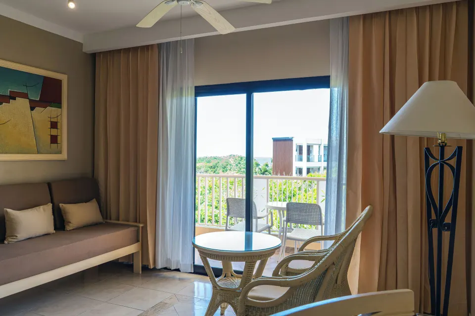 Junior Suite seating area and balcony doors with outdoor view at Bahia Principe Luxury Akumal