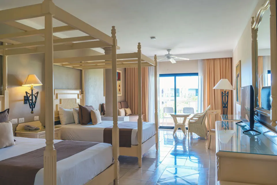 Junior Suite with two canopy beds, seating area and balcony at Bahia Principe Luxury Akumal