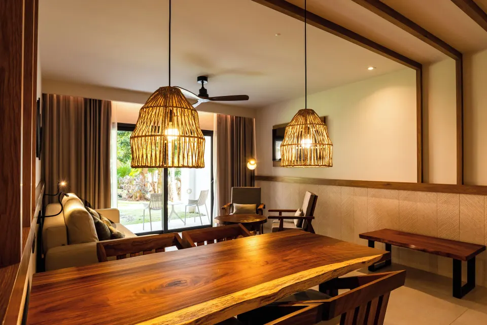 Wooden dining table and woven pendant lights facing the terrace in a two‑bedroom suite at Bahia Principe Luxury Akumal