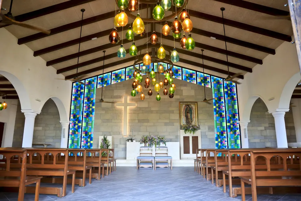 Resort chapel interior with wooden pews, stained glass and altar at Bahia Principe Luxury Akumal