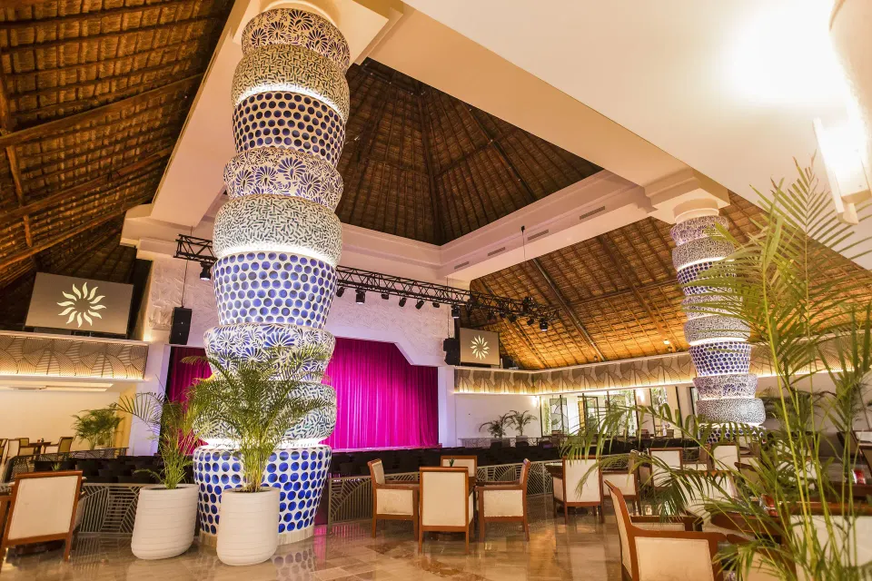 Indoor resort event stage with decorative columns and seating at Bahia Principe Luxury Akumal