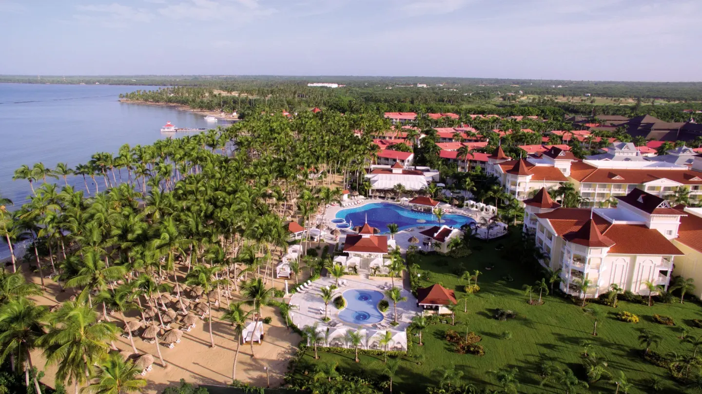 Aerial view of beach, pools and red-roofed buildings at Bahia Principe Luxury Bouganville.