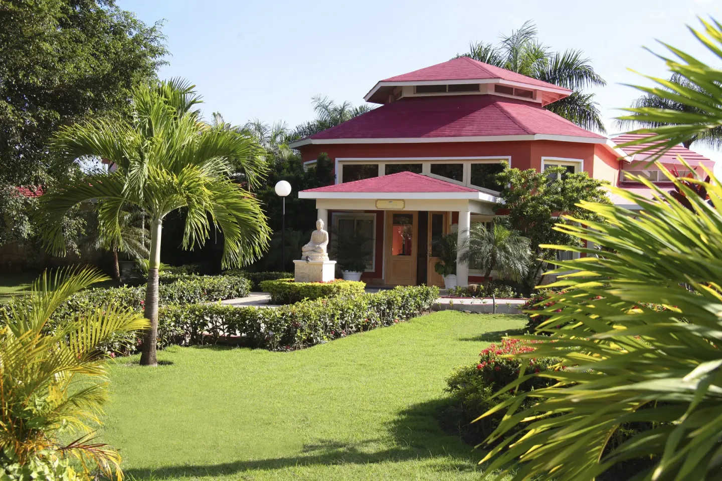 Red-roofed spa building set in tropical gardens at Bahia Principe Luxury Bouganville.