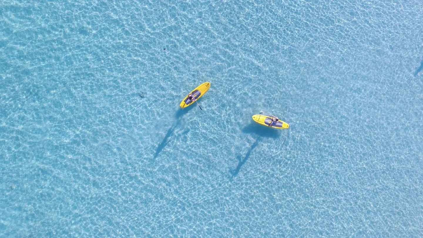 Two yellow kayaks glide over clear shallow water at Bahia Principe Luxury Bouganville.