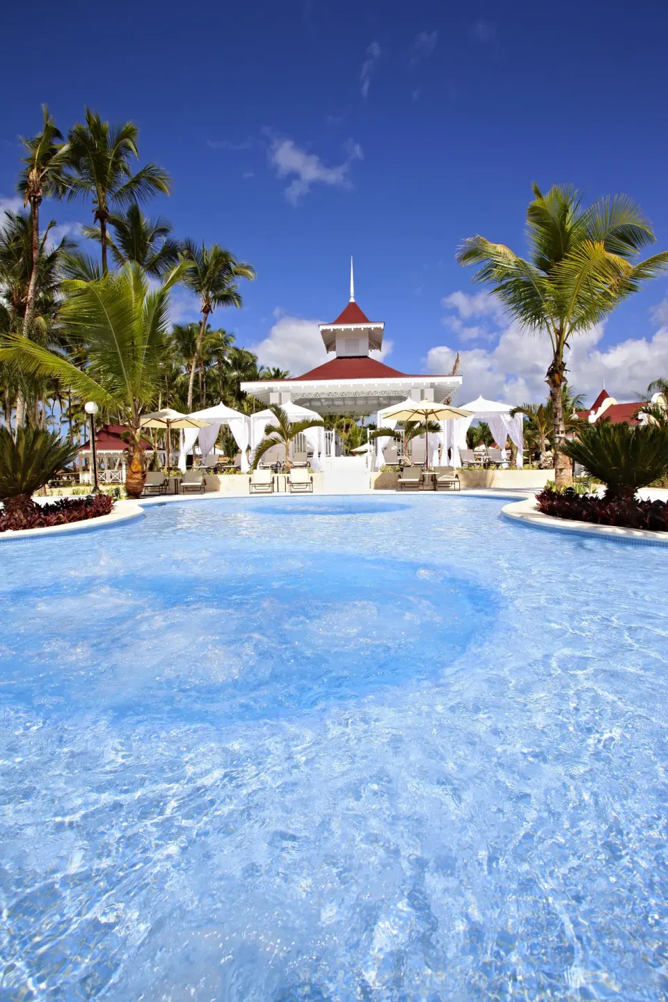 Curved pool facing a white pavilion at Bahia Principe Luxury Bouganville.