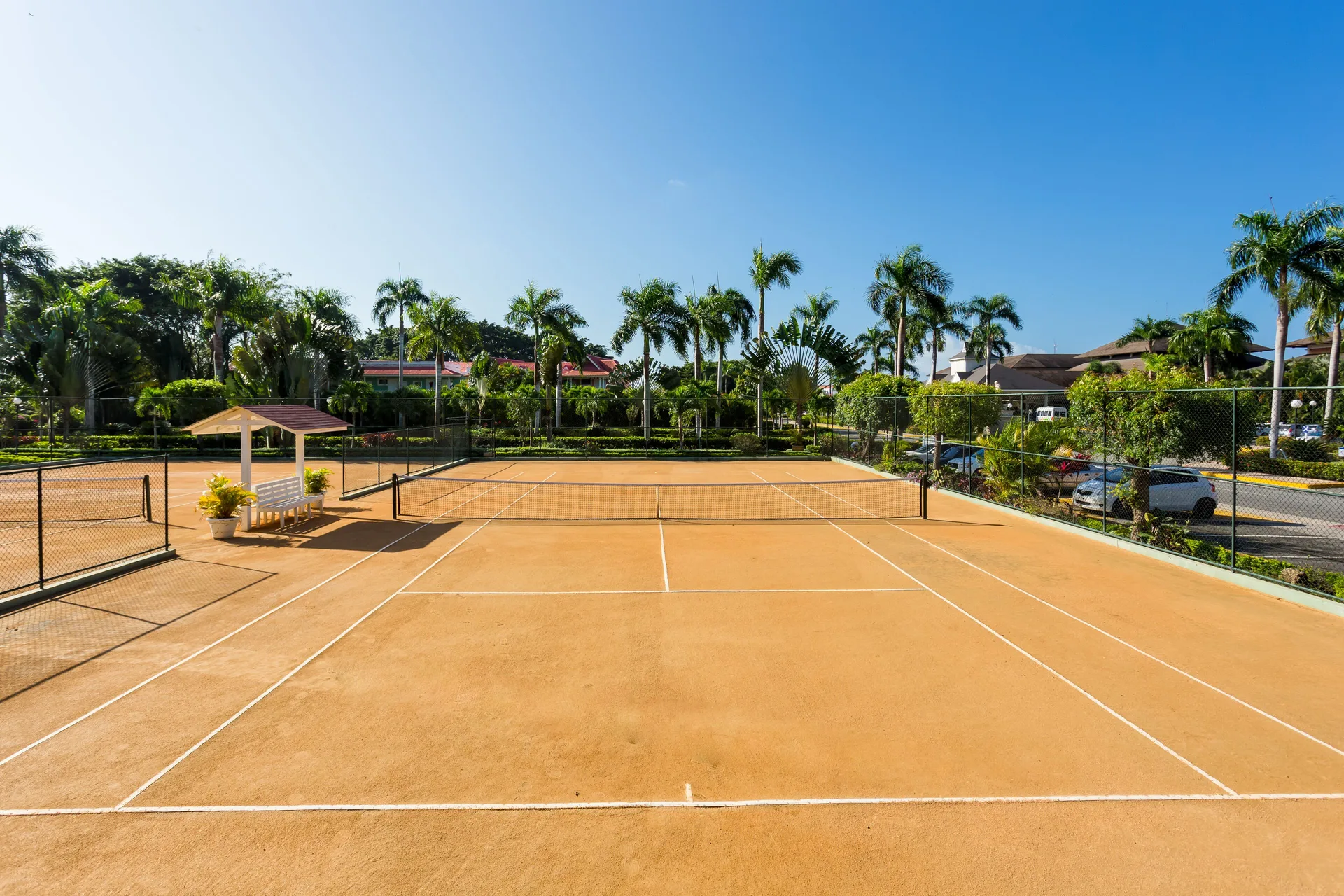 Empty tennis courts bordered by palms and landscaping at Bahia Principe Luxury Bouganville.