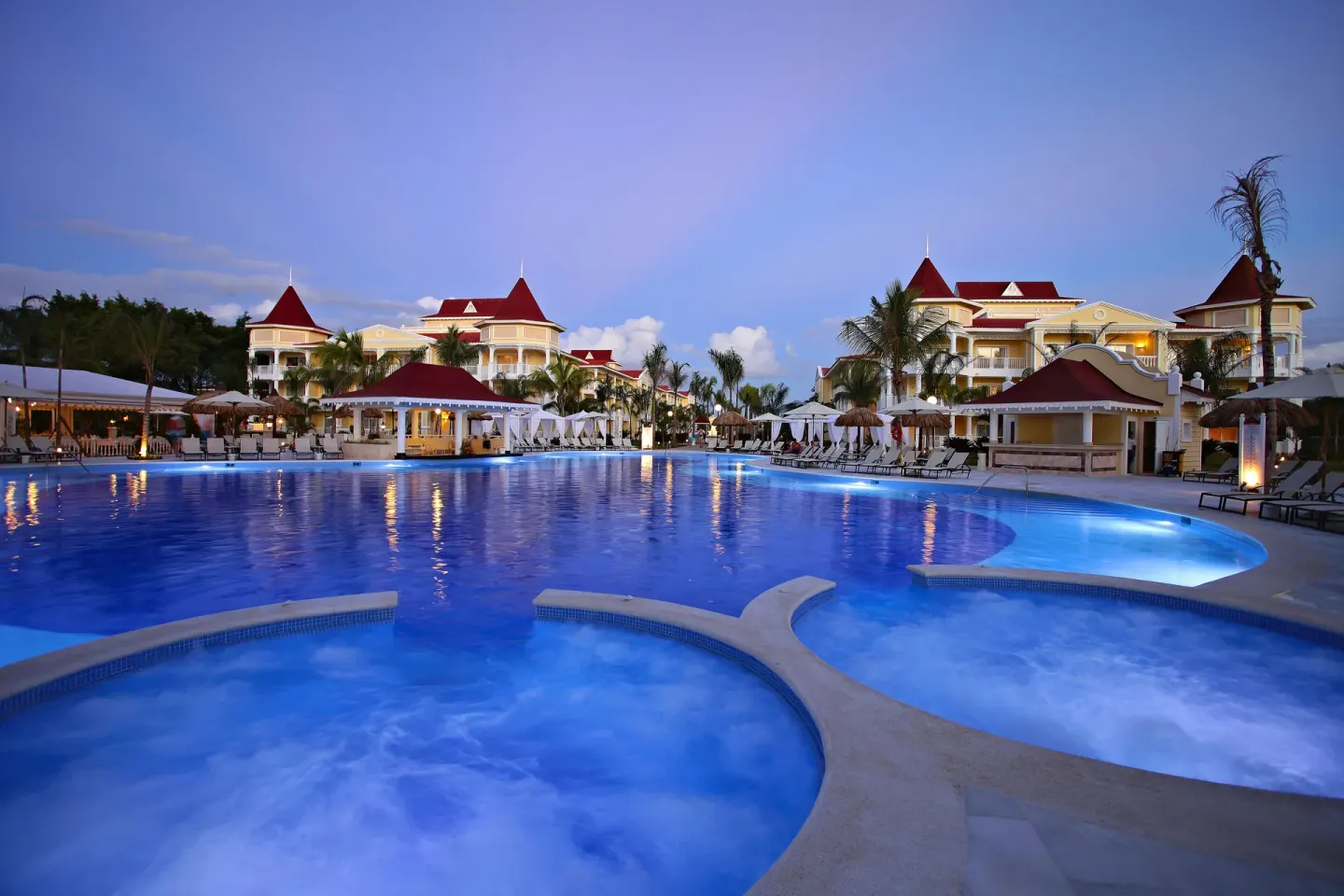 Large evening pool with resort buildings at Bahia Principe Luxury Bouganville.