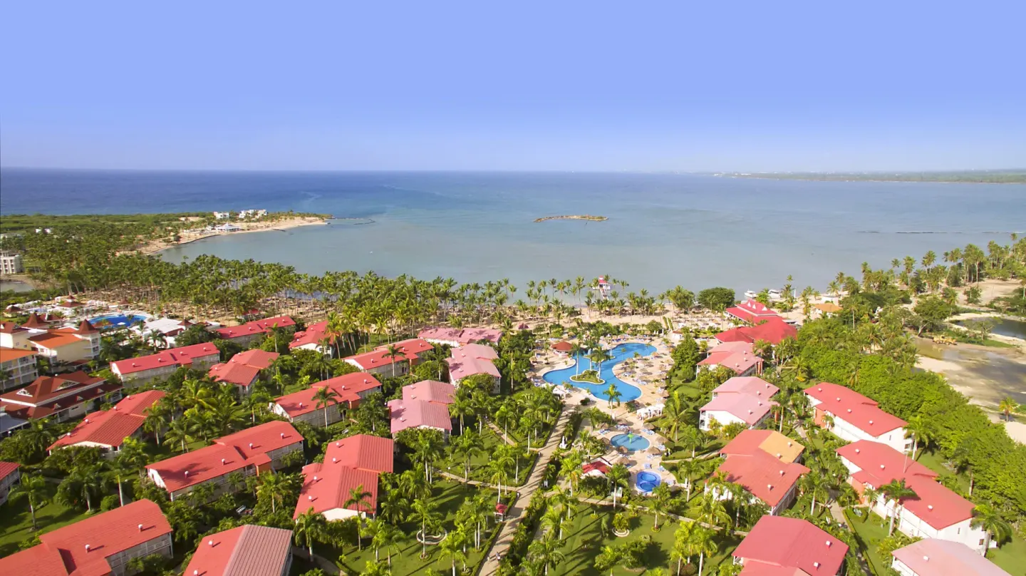 Wide aerial view of resort buildings, pools and bay at Bahia Principe Luxury Bouganville.