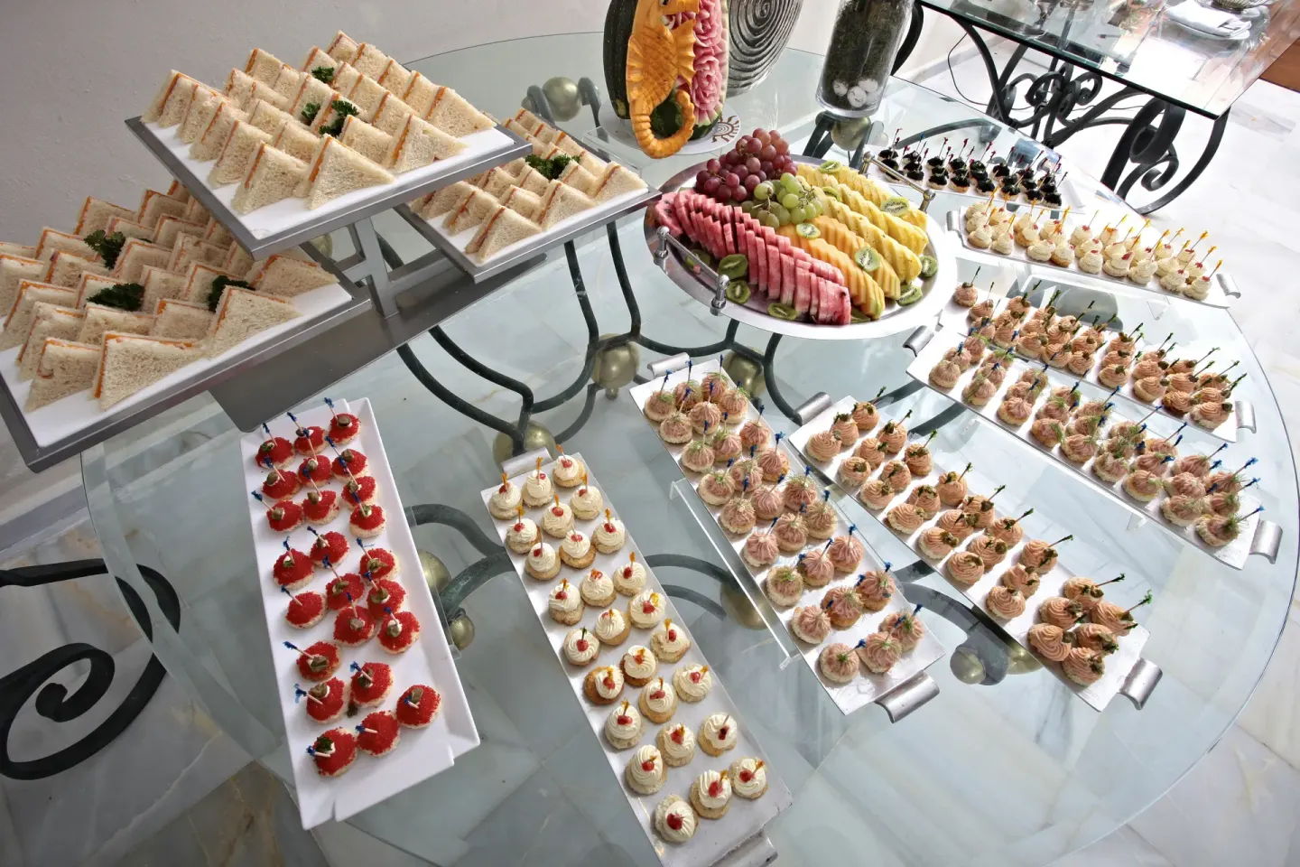 Assorted sandwiches, fruit, and bite-size appetizers at Bahia Principe Luxury Bouganville.