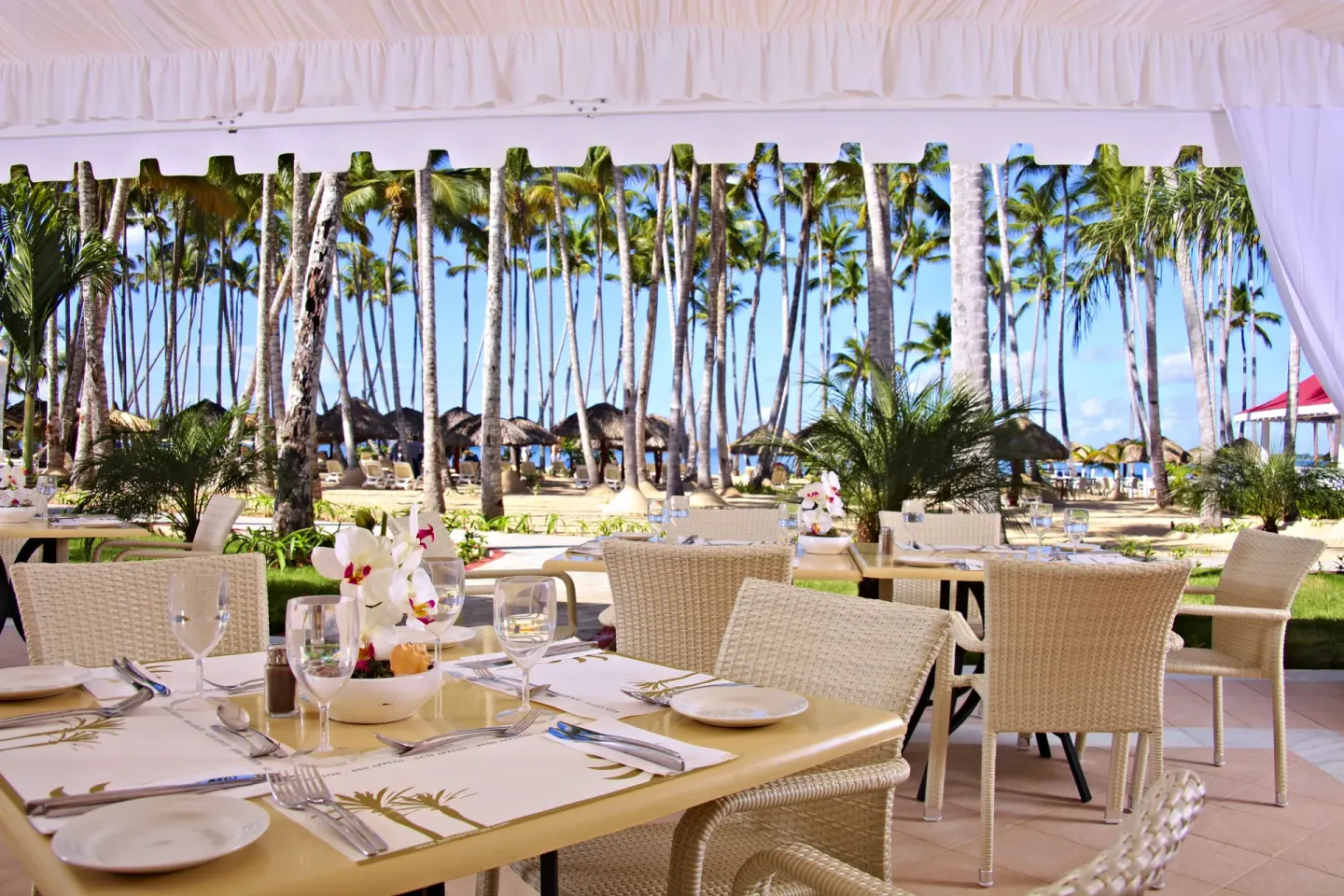 Beachside dining terrace with set tables at Bahia Principe Luxury Bouganville.