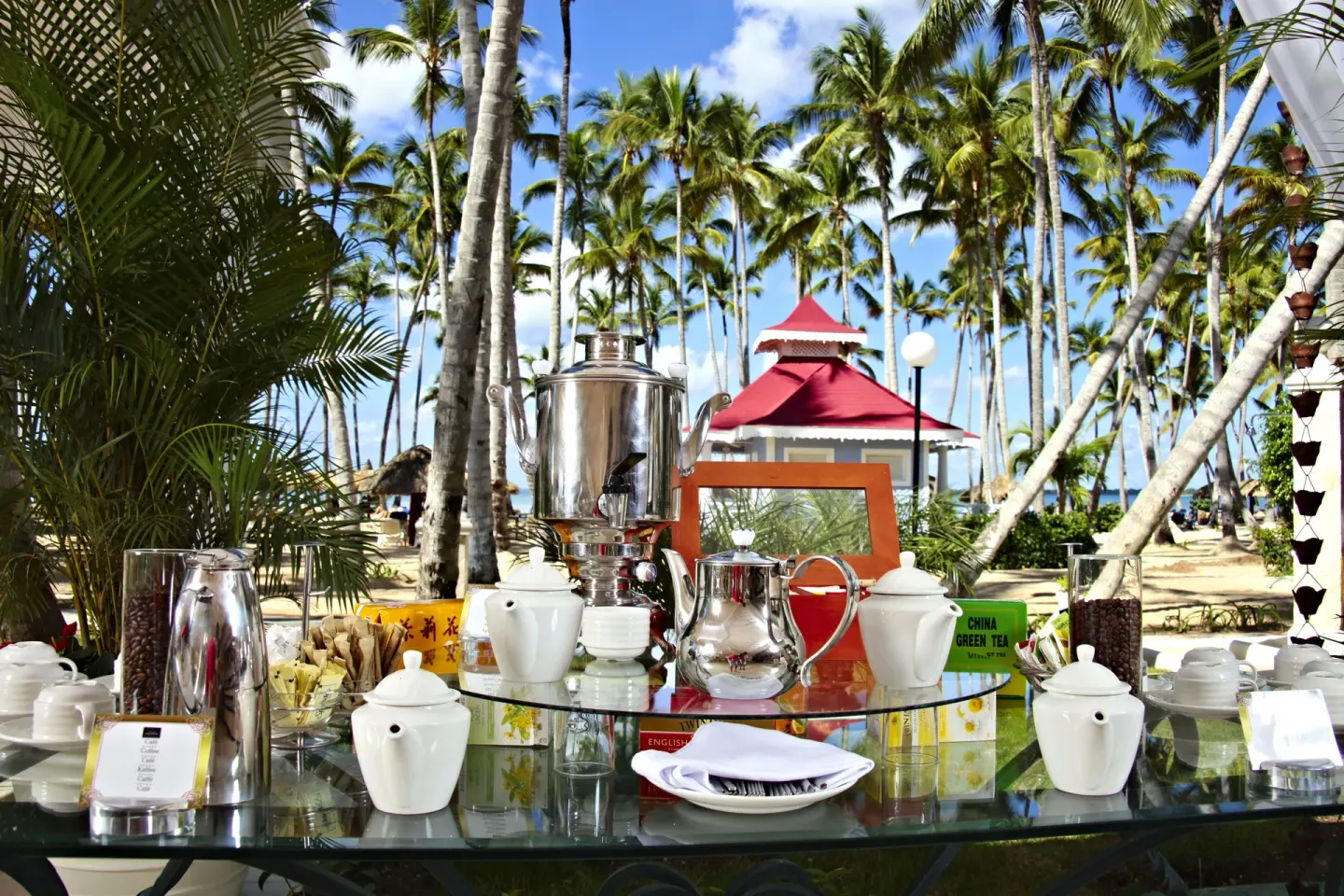 Outdoor tea and coffee service set beneath palms at Bahia Principe Luxury Bouganville.