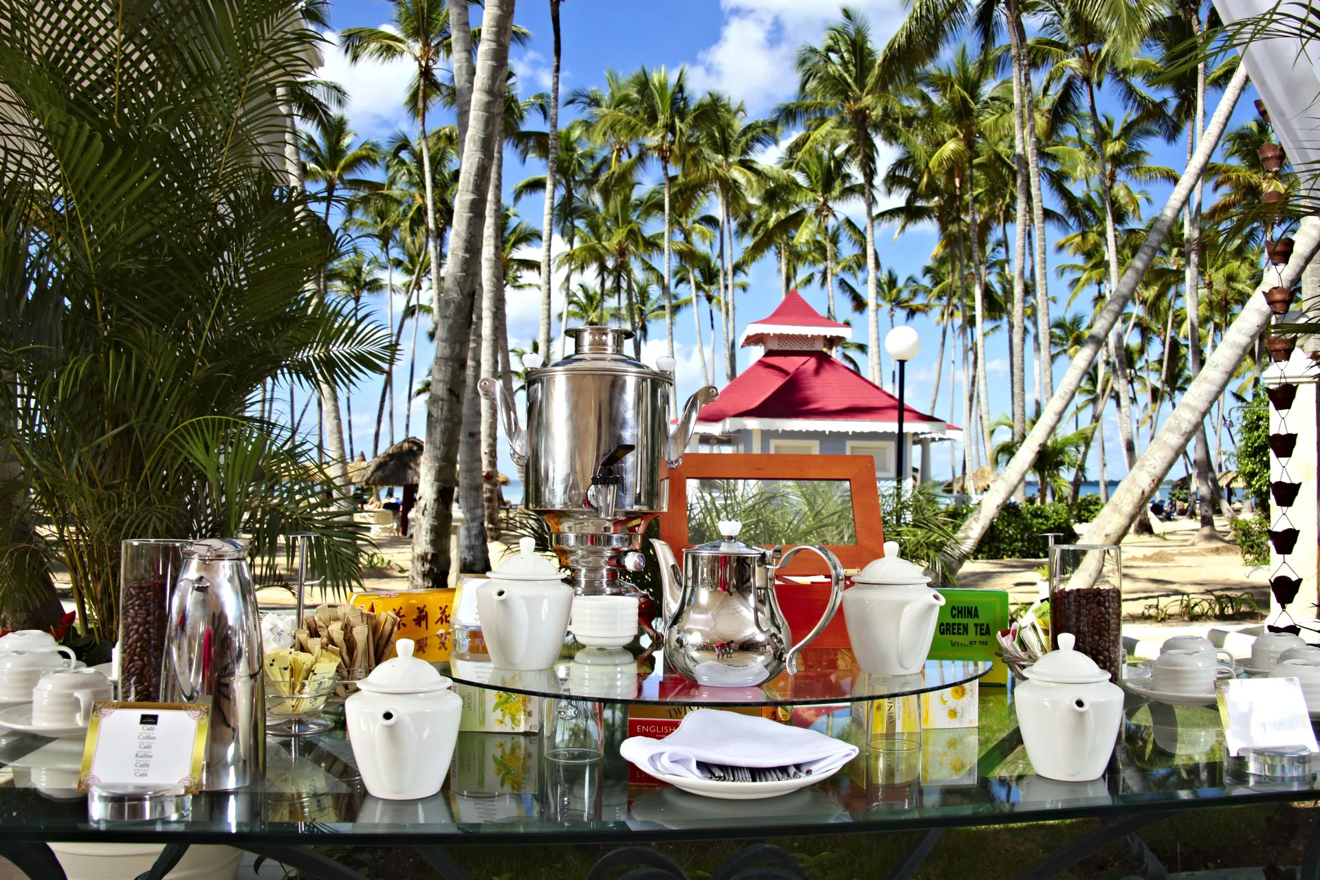 Outdoor tea and coffee service set beneath palms at Bahia Principe Luxury Bouganville.
