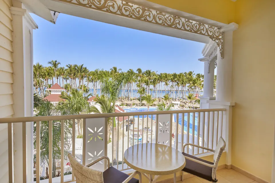 Junior Suite balcony with pool, palms and ocean view at Bahia Principe Luxury Bouganville.