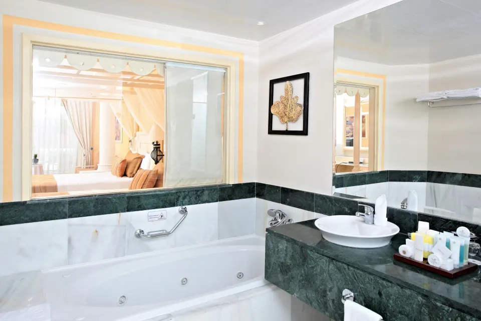 Junior Suite deluxe bathroom with tub, sink, and bath amenities at Bahia Principe Luxury Bouganville.