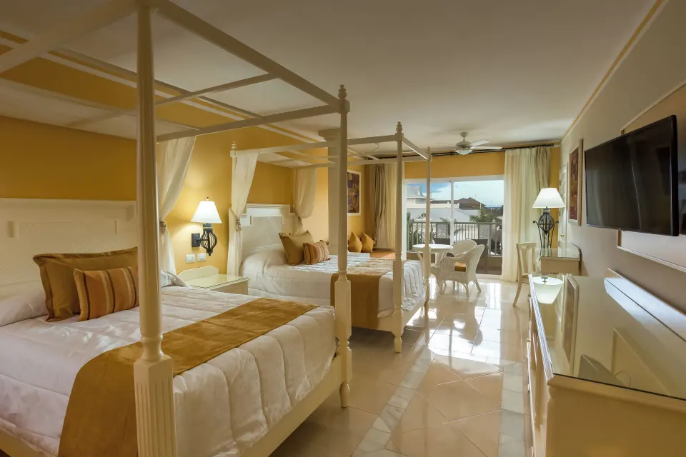 Junior Suite with two canopy beds and balcony at Bahia Principe Luxury Bouganville.