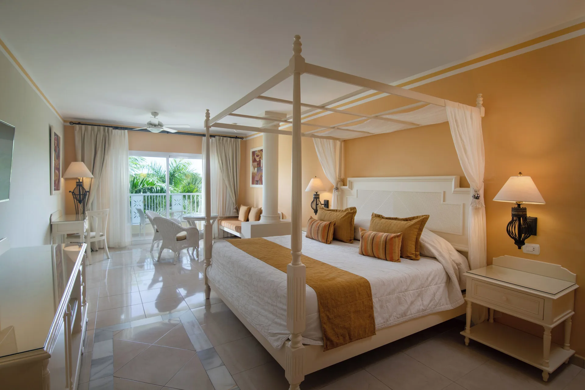 Junior Suite bedroom with canopy bed and balcony at Bahia Principe Luxury Bouganville.