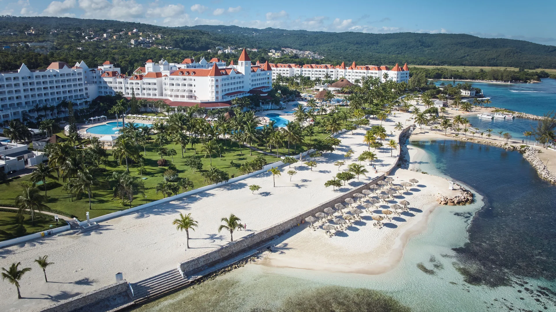 Aerial view of beach, pools and white resort buildings at Bahia Principe Luxury Runaway Bay.
