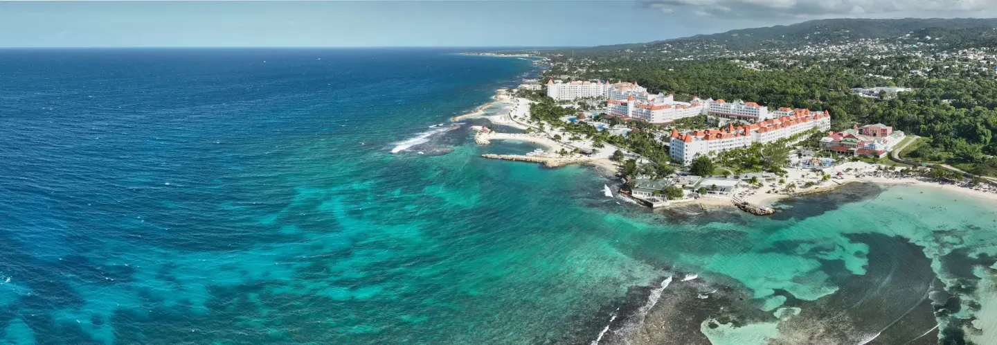 Aerial coastline view of Bahia Principe Luxury Runaway Bay beside turquoise reef water.