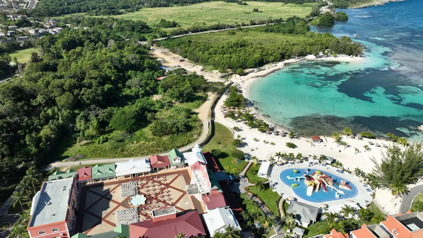 Aerial view of turquoise cove, beach and activity pool at Bahia Principe Luxury Runaway Bay.