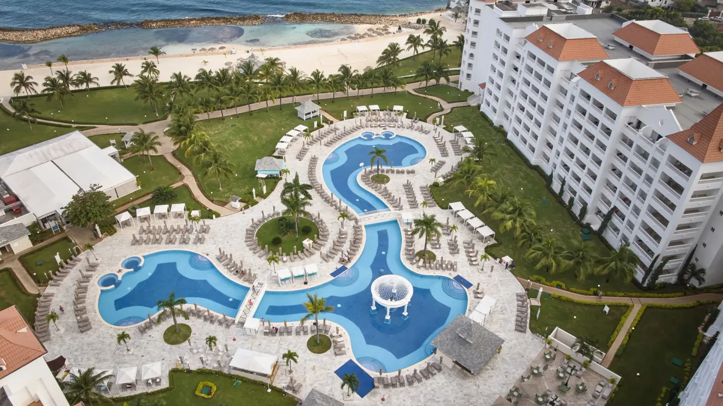 Aerial view of resort pools, loungers and beachfront buildings at Bahia Principe Luxury Runaway Bay.