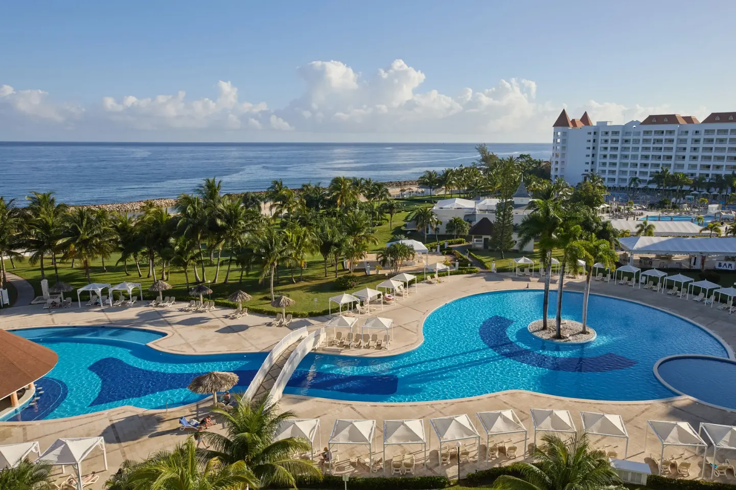 Aerial resort view with pools, palms, ocean and guest buildings at Bahia Principe Luxury Runaway Bay.