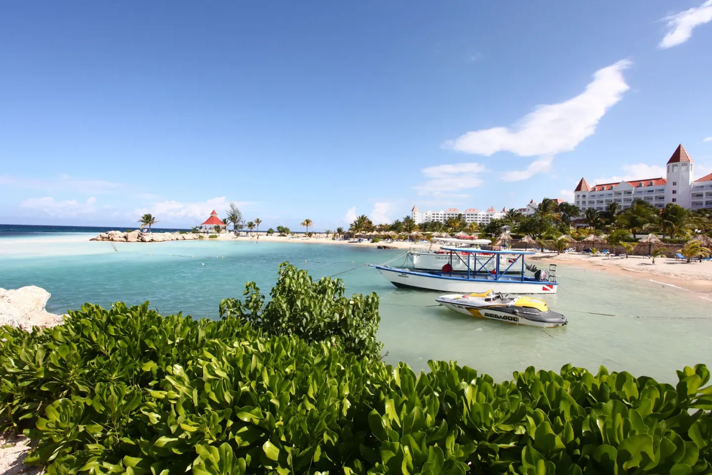 Beach cove with boats and resort buildings at Bahia Principe Luxury Runaway Bay.