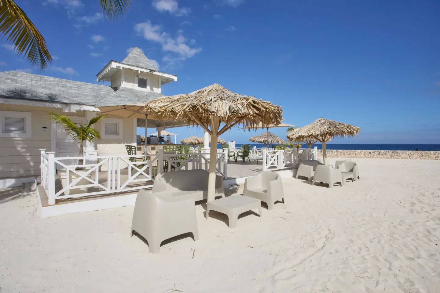 Beach loungers and thatched umbrellas on the sand at Bahia Principe Luxury Runaway Bay.