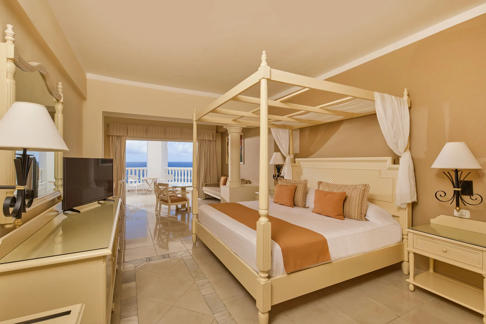 Guest room with canopy king bed and ocean-facing balcony at Bahia Principe Luxury Runaway Bay.