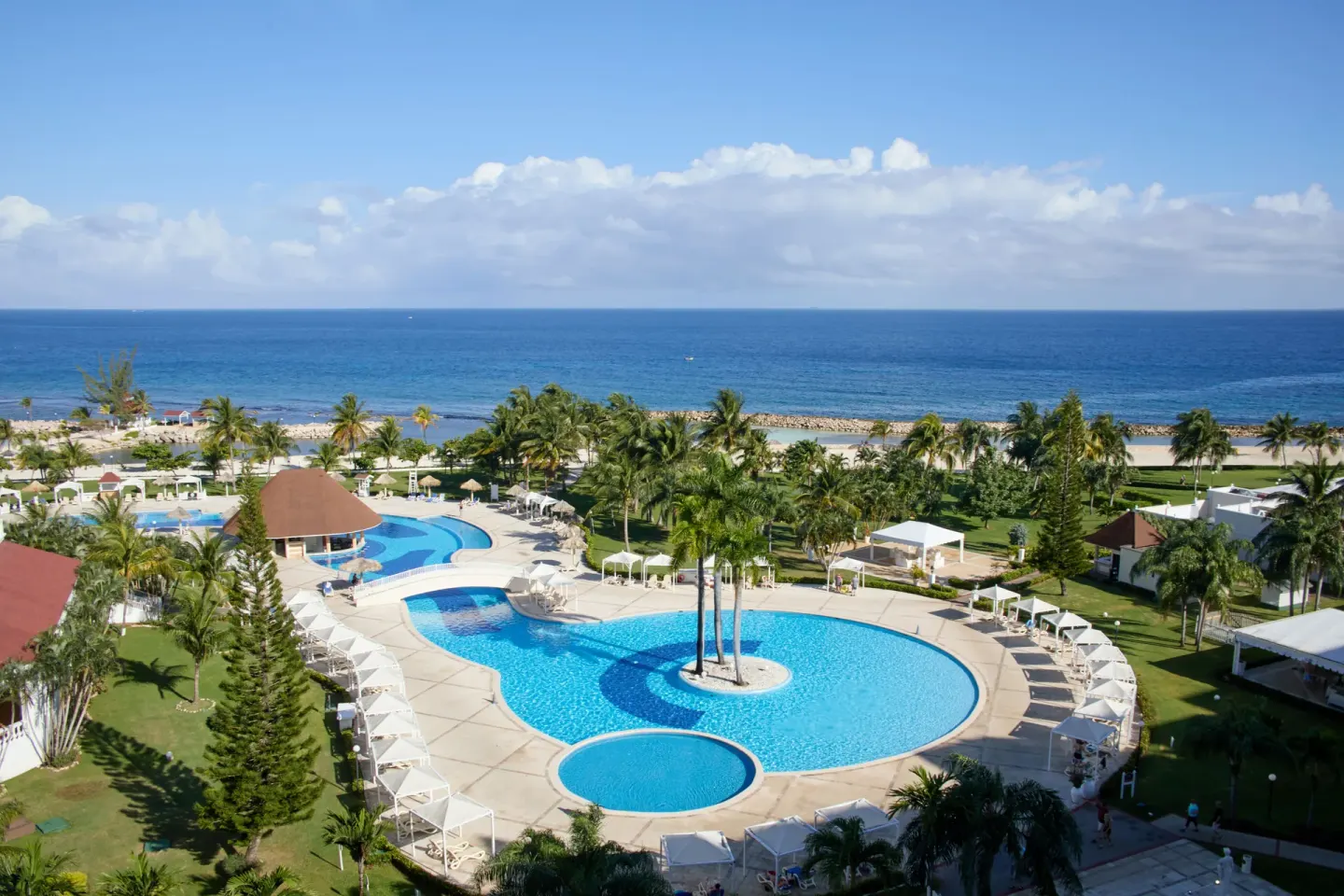 High view of circular pools, gardens, beach and ocean at Bahia Principe Luxury Runaway Bay.