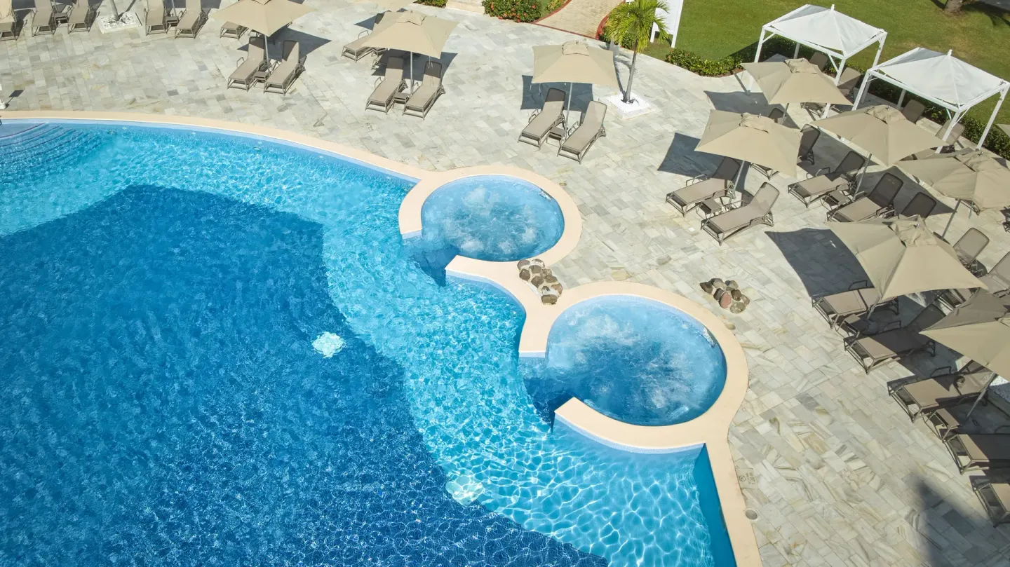Overhead view of the pool edge, two round whirlpools and sun loungers at Bahia Principe Luxury Runaway Bay.