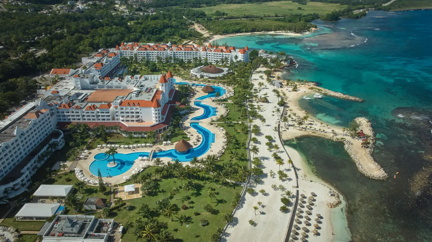 Wide aerial view of pools, beach and turquoise shoreline at Bahia Principe Luxury Runaway Bay.