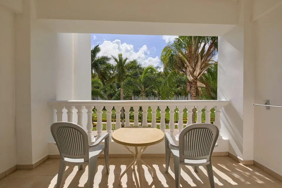 Junior Suite Deluxe balcony with chairs and palms at Bahia Principe Luxury Runaway Bay.