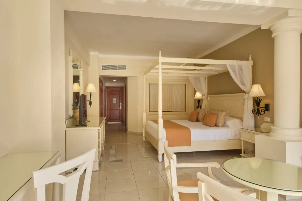 Junior Suite deluxe bed area with table and entry hall at Bahia Principe Luxury Runaway Bay.