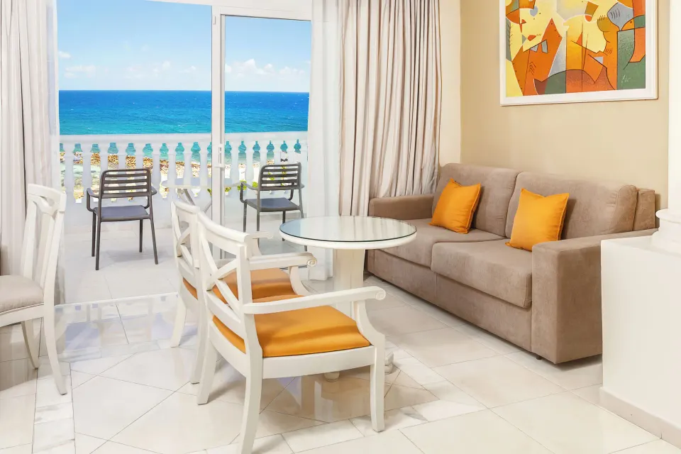 Junior Suite Sea View sofa area beside a turquoise ocean balcony at Bahia Principe Luxury Runaway Bay.