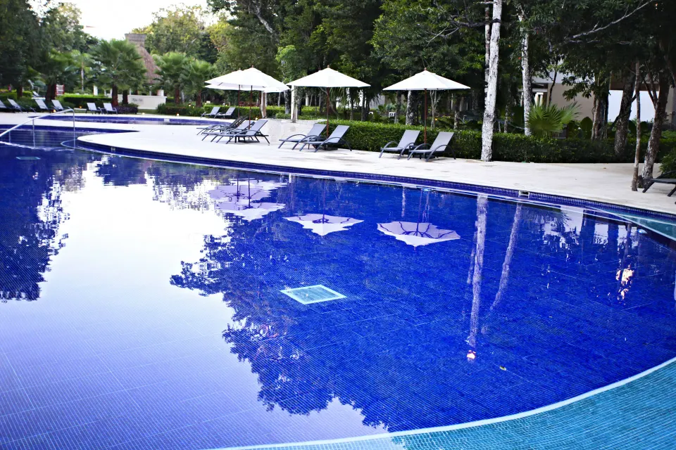 Curved blue resort pool with loungers and umbrellas at Bahia Principe Luxury Sian Ka'an