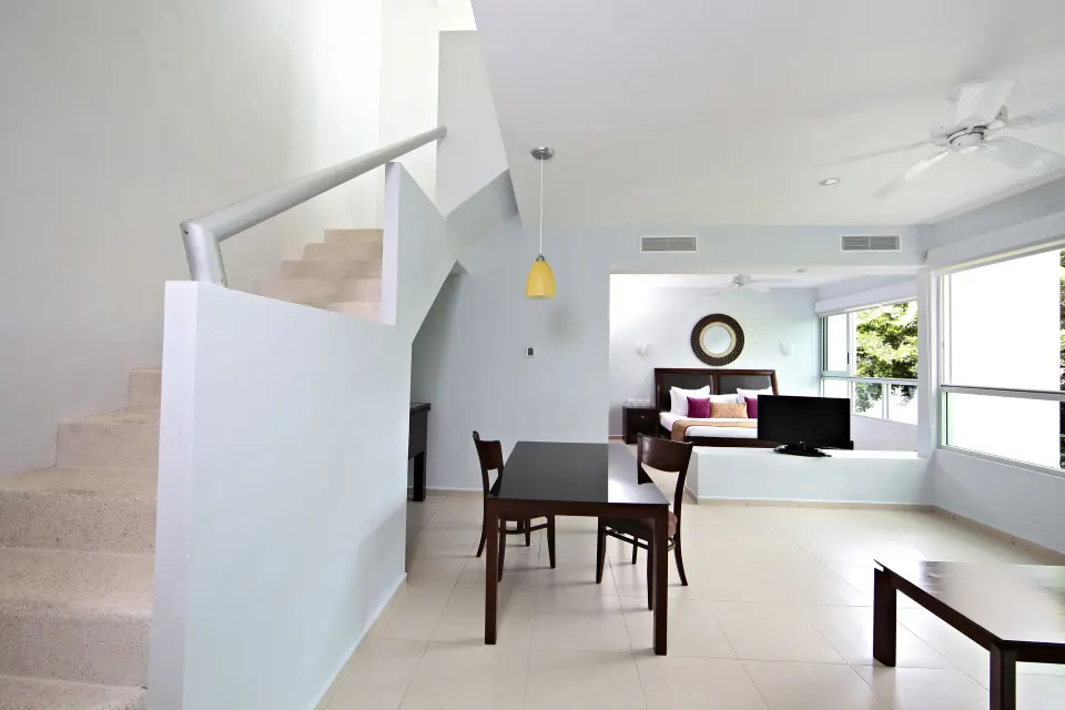 Open-plan junior suite living area with stair and dining table at Bahia Principe Luxury Sian Ka'an