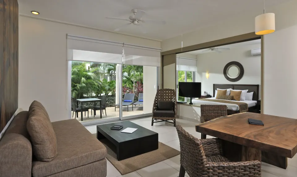 Suite living room with sliding glass doors opening to a private patio and lush plants at Bahia Principe Luxury Sian Ka'an