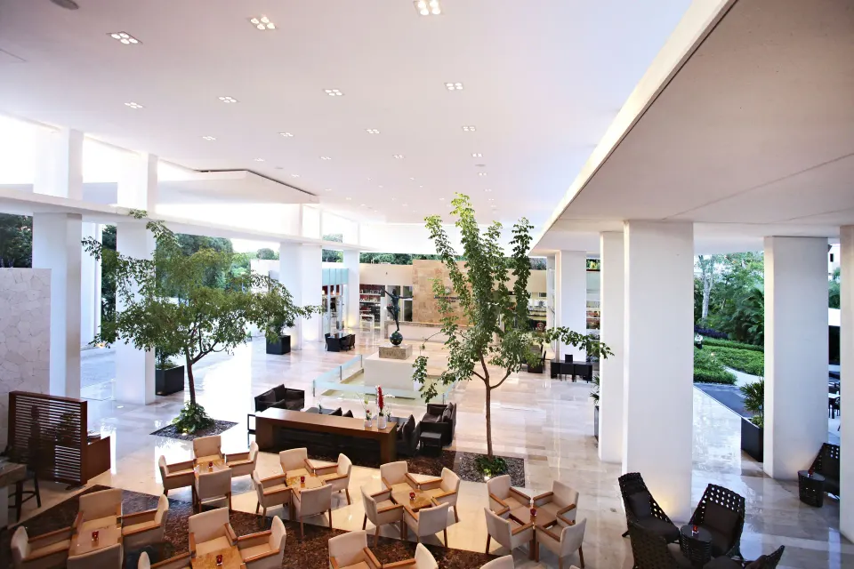 Spacious bright resort lobby with seating areas and indoor trees at Bahia Principe Luxury Sian Ka'an