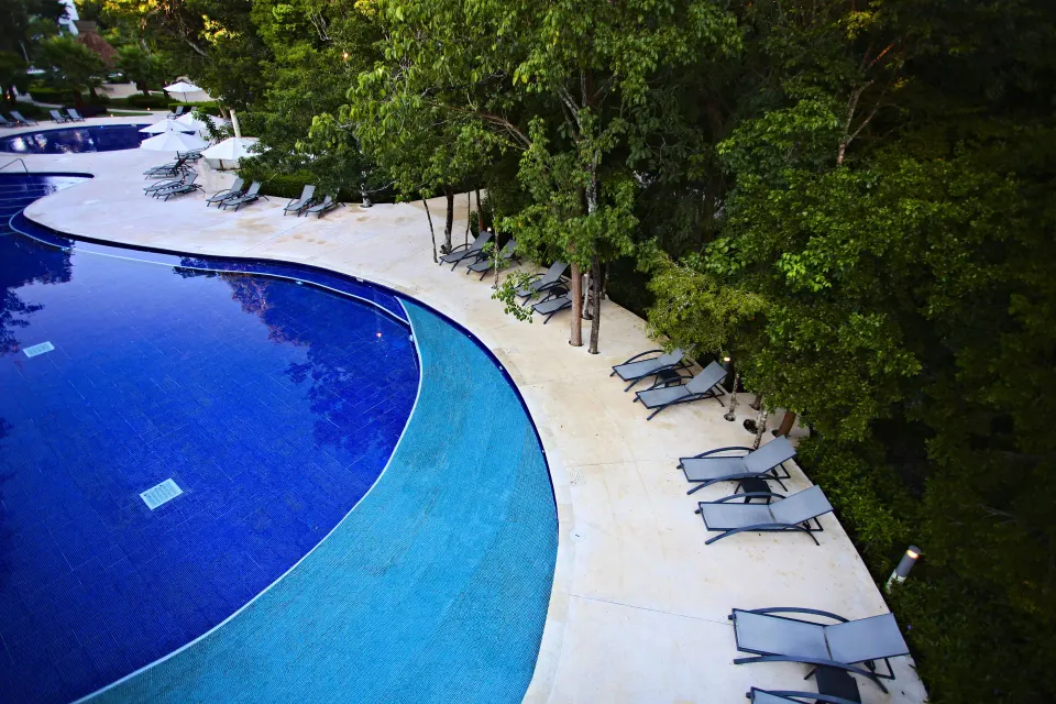 Aerial view of resort pool edge with loungers beside jungle foliage at Bahia Principe Luxury Sian Ka'an
