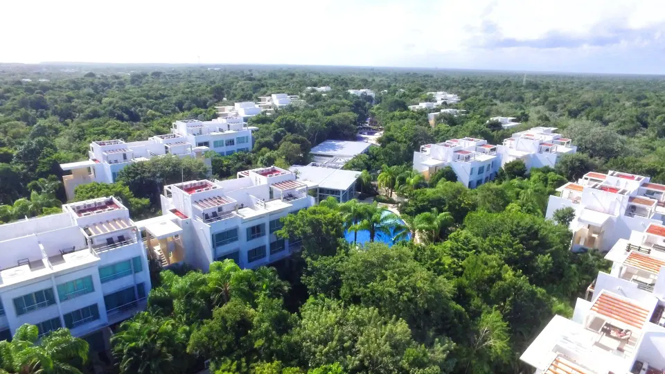 Wide aerial view of the resort rooftops, pools and surrounding forest at Bahia Principe Luxury Sian Ka'an