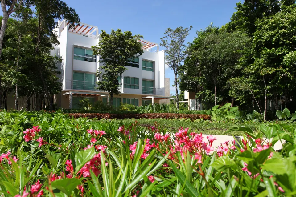 Low-rise resort building framed by flowering foreground gardens at Bahia Principe Luxury Sian Ka'an