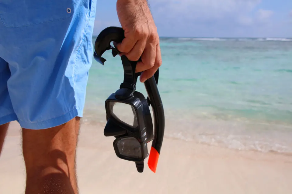 Guest holding snorkel gear on the beach at Bahia Principe Luxury Sian Ka'an