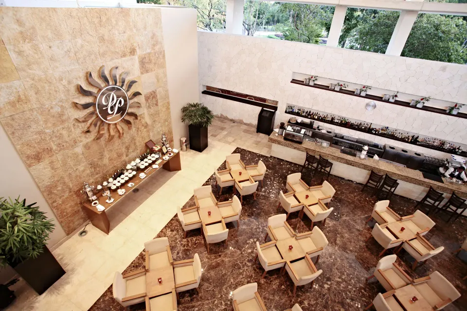 Indoor restaurant seating with buffets and a decorative sun emblem at Bahia Principe Luxury Sian Ka'an